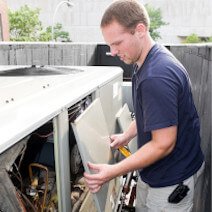 A technician fixing an air-conditioning unit | Heating and Cooling